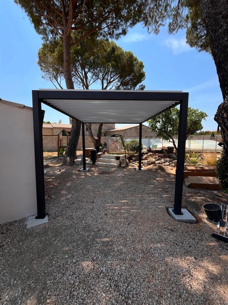 Pose d’une pergola bioclimatique à lames orientables dans un jardin méditerranéen à Pujaut, à l’ombre des pins parasols.